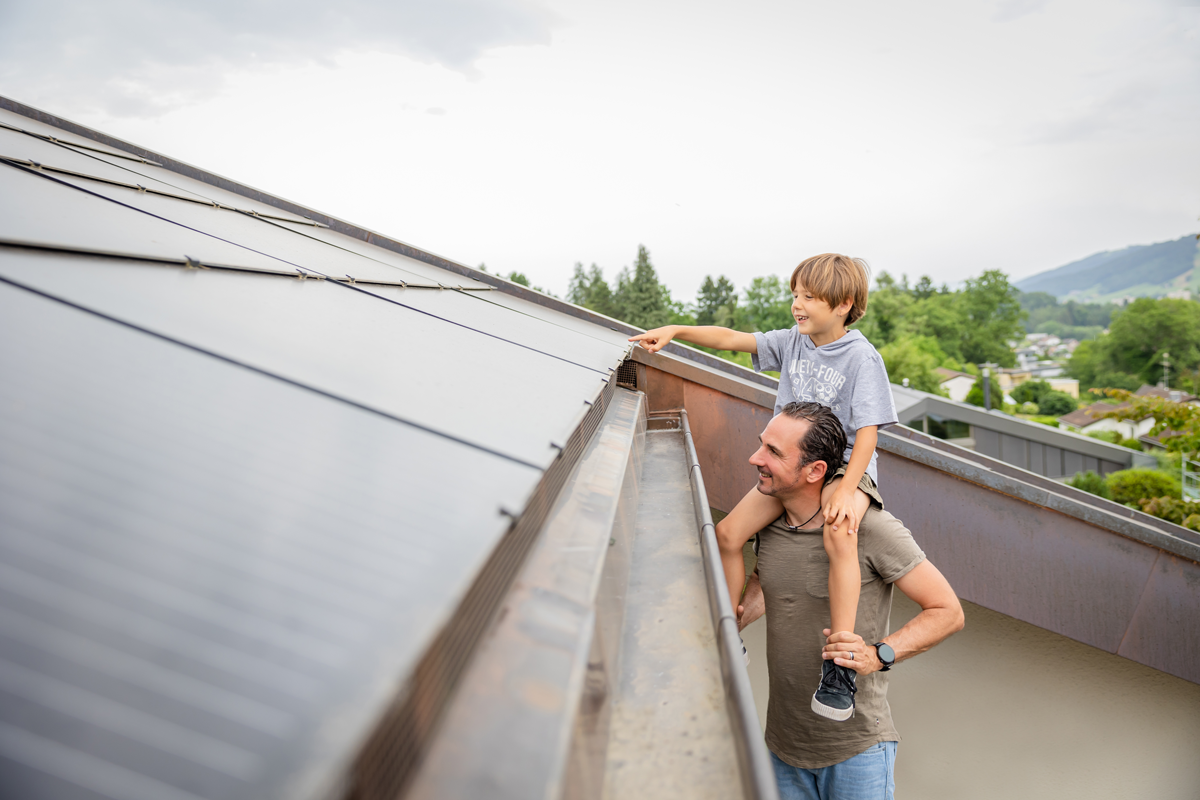 Vater mit Sohn auf den Schultern schaut sich eine Photovoltaikanlage an